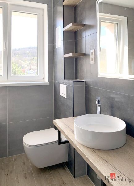 Badezimmer in einer Einzimmerwohnung mit Waschbecken und Boden in Holzoptik.