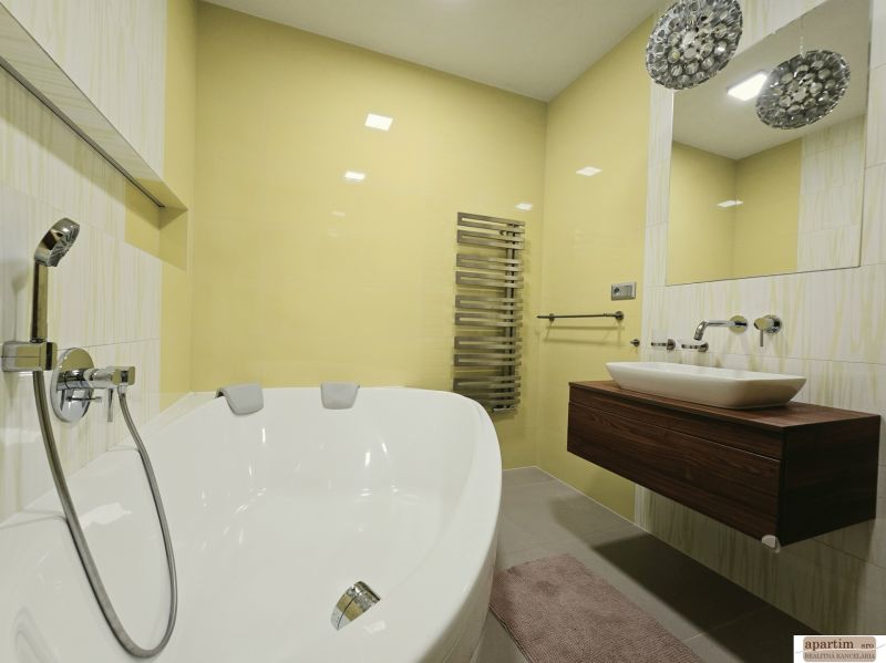 Badezimmer mit Badewanne in einer 4-Zimmer-Wohnung, mit gelben Fliesen und modernem Waschbecken.