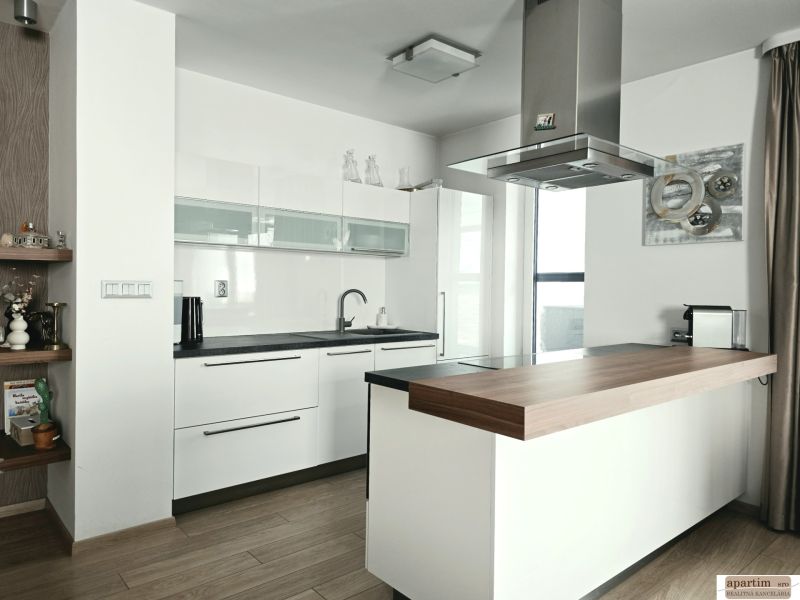 Küche in einer 4-Zimmer-Wohnung mit Küchenzeile und Insel, Boden mit Holzdekor.