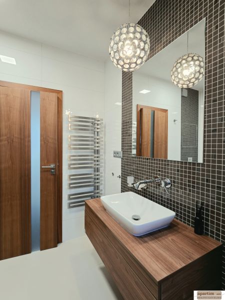 Badezimmer mit hängendem Waschbecken, Holzelementen und Mosaik in einer 4-Zimmer-Wohnung.