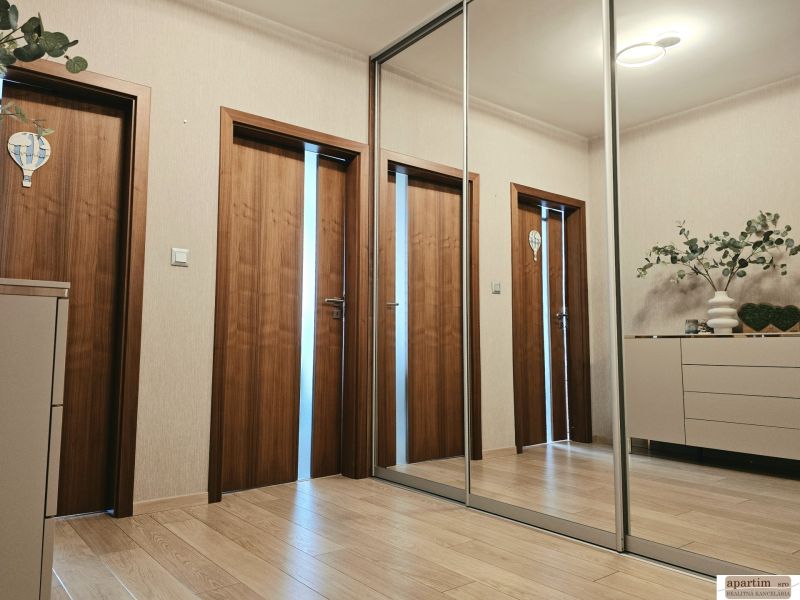 Flur mit einem Spiegelschrank, einem Boden mit Holzdekor und Türen in einer 4-Zimmer-Wohnung.