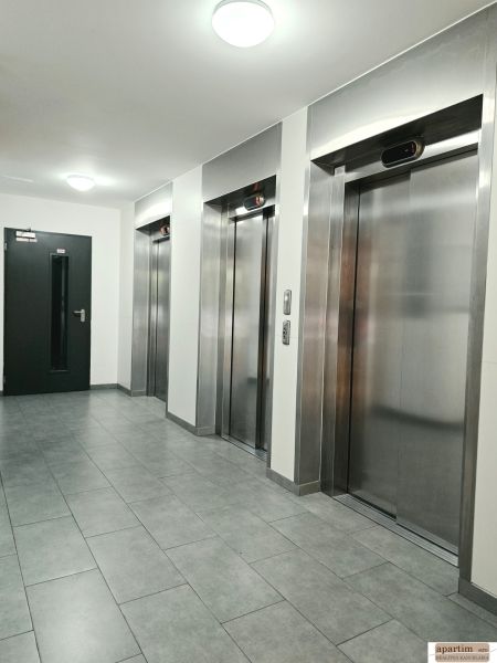 Ein Flur mit vier Metallaufzügen und grauen Fliesen in einer Vierzimmerwohnung.