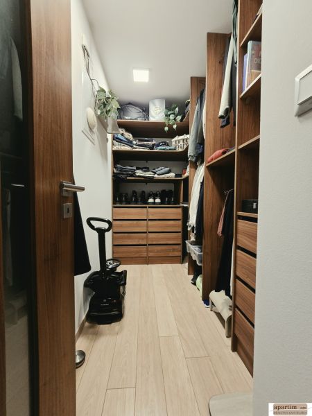 Ein Kleiderschrank mit Schränken und Regalen in einer 4-Zimmer-Wohnung mit einem Boden in Holzoptik.