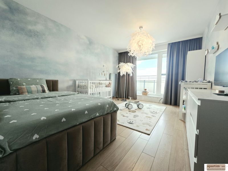 Schlafzimmer in einer 4-Zimmer-Wohnung mit Holzboden, Bett und Kinderbett.