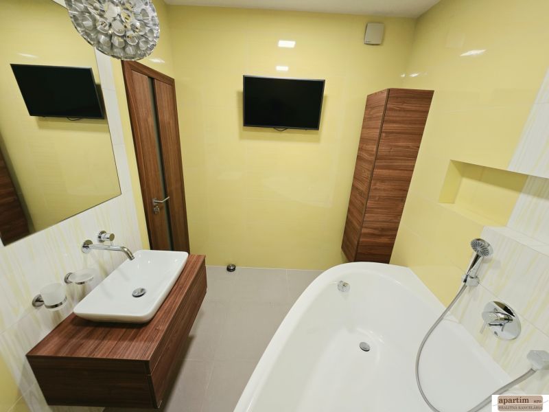 Badezimmer mit hellgelben Wänden, Badewanne, Waschbecken und Spiegel in einer 4-Zimmer-Wohnung.
