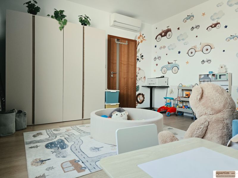 Kinderzimmer in einer 4-Zimmer-Wohnung mit bunten Möbeln, Wanddekorationen und einem Boden in Holzoptik.