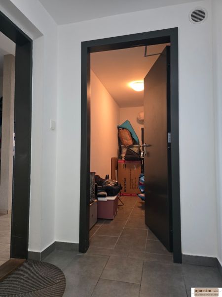 Flur mit grauen Fliesen und einem Abstellraum in einer 4-Zimmer-Wohnung.