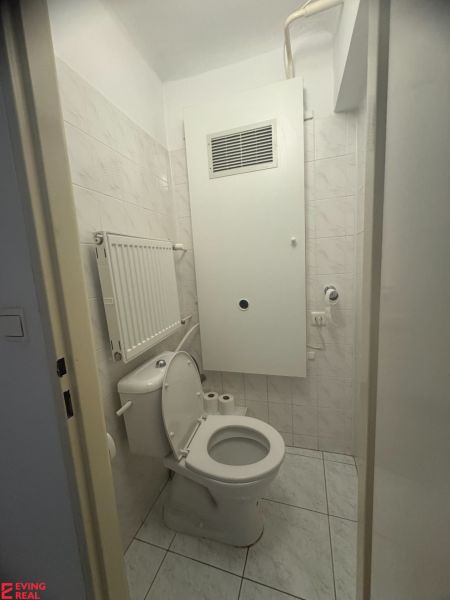 Badezimmer in einer Einzimmerwohnung mit Toilette, hellen Fliesen und Heizkörper.