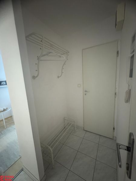 Flur mit Garderobe und Schuhschrank in einer Einzimmerwohnung mit Fliesenboden.