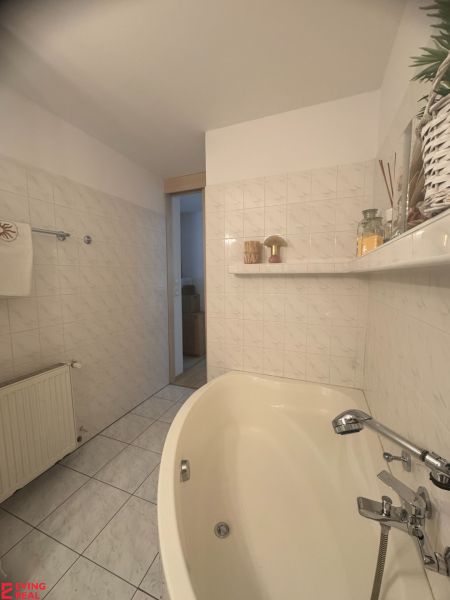 Badezimmer in einer Einzimmerwohnung mit Badewanne, Keramikfliesen und Dekorationen.