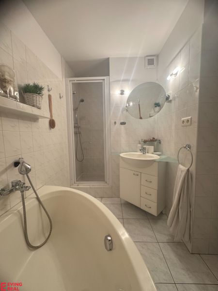 Badezimmer mit Badewanne, Waschbecken und Dusche in einer Einzimmerwohnung.
