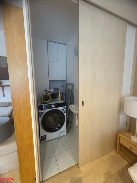 Badezimmer in einer Einzimmerwohnung mit Waschmaschine und Schiebetüren, Boden mit Holzdekor.