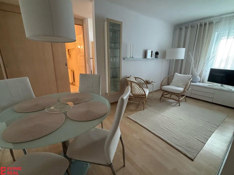 Heller Wohnraum mit Esstisch und Holzboden in einer Einzimmerwohnung.