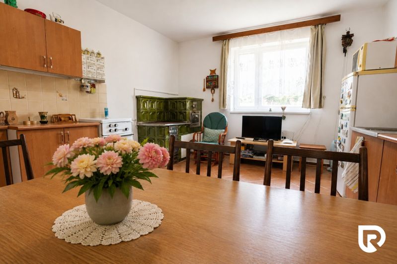 Küche in einem Einfamilienhaus mit Kachelherd, Esstisch und Blumendekoration.