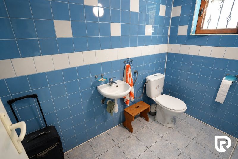 Badezimmer in einem Einfamilienhaus mit blauen Fliesen, Waschbecken und WC.