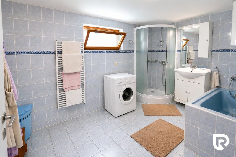 Badezimmer in einem Einfamilienhaus mit Badewanne, Dusche und Waschmaschine.