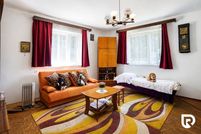 Wohnzimmer in einem Einfamilienhaus mit einem orangefarbenen Sofa, einem Teppich mit buntem Muster und Holzelementen.