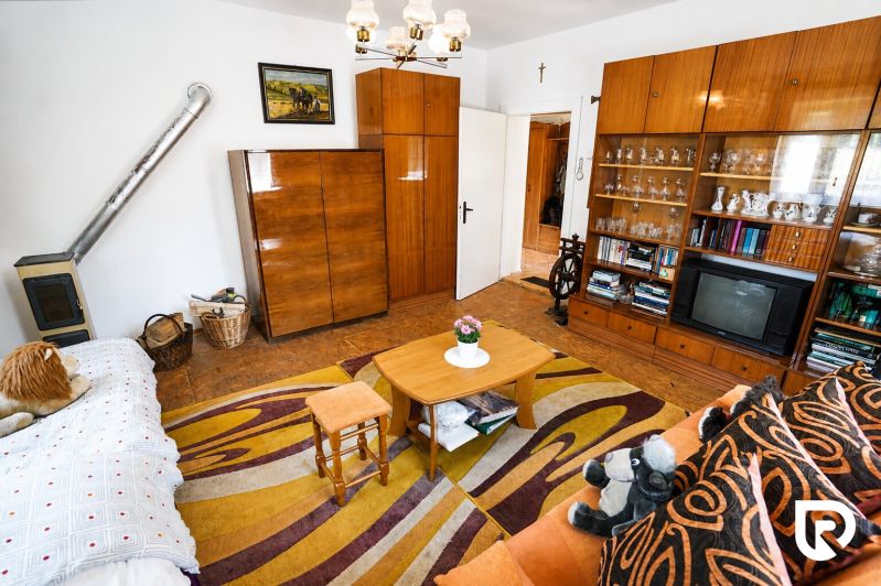 Wohnzimmer in einem Einfamilienhaus mit Teppich, Möbeln, Fernseher und Ofen.
