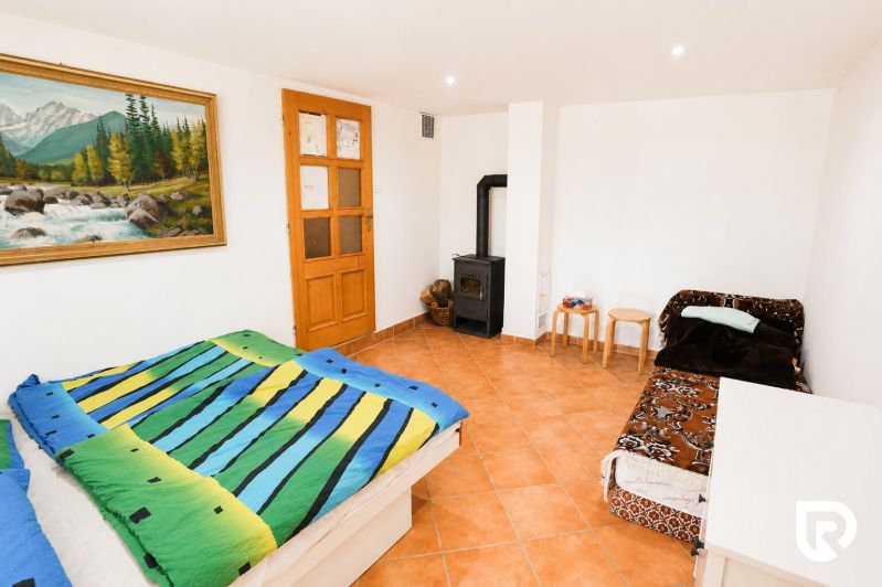 Schlafzimmer mit bunter Bettwäsche, Sofa, Kamin und Bild in einem Einfamilienhaus.