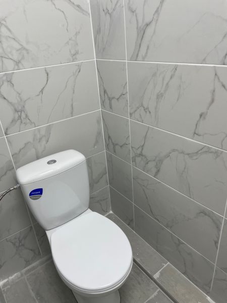 Toilette mit Marmorverkleidung in Geschäftsräumen, grauer Boden.