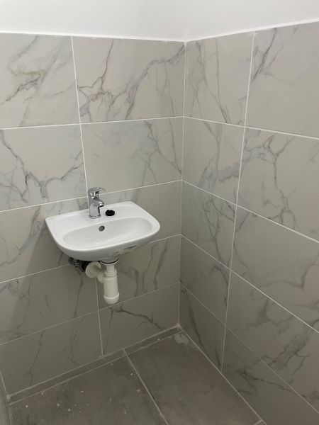 Waschbecken und Fliesen in Geschäftsräumen mit Marmoroptik.
