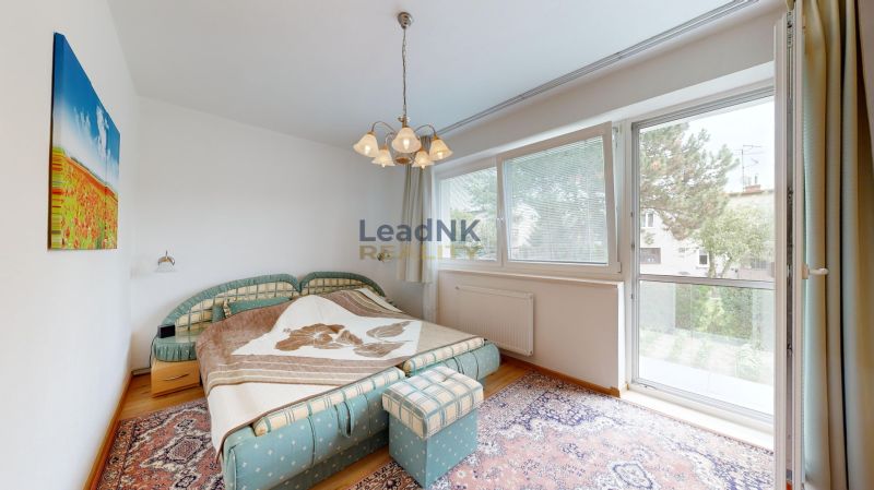 Schlafzimmer in einer 3-Zimmer-Wohnung mit großem Fenster, buntem Teppich und Doppelbett.