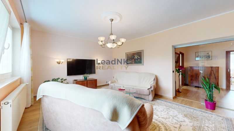 Wohnzimmer in einer 3-Zimmer-Wohnung mit Sofa, Fernseher und hellem Teppich.