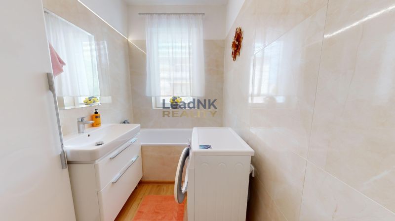 Badezimmer in einer 3-Zimmer-Wohnung mit Badewanne, Waschbecken, Waschmaschine und Fenster.