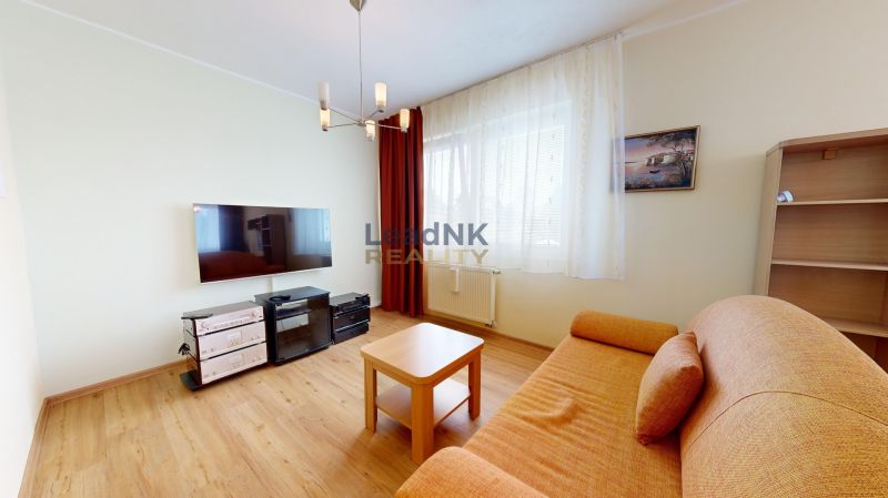 Wohnzimmer in einer 3-Zimmer-Wohnung mit Holzboden, Sofa und Fernseher.