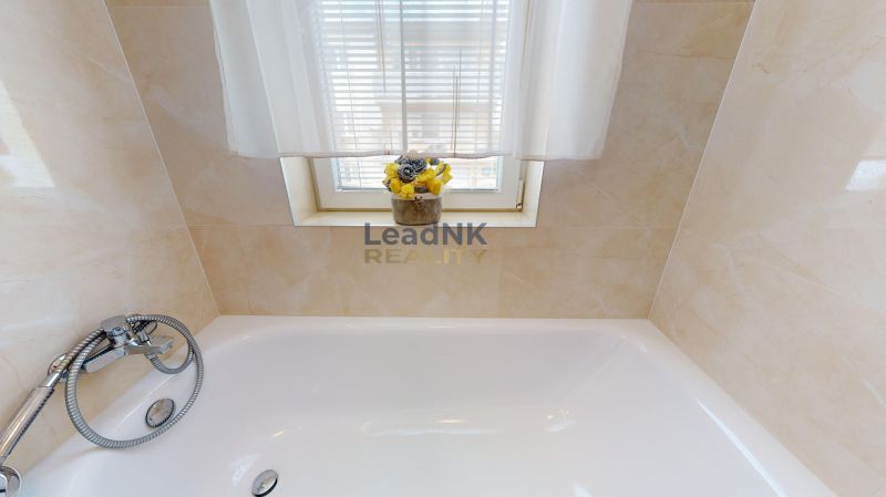 Badezimmer mit Duscharmatur, Badewanne und Blumen auf der Fensterbank in einer 3-Zimmer-Wohnung.