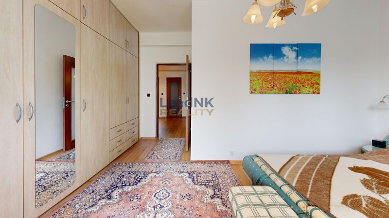 Schlafzimmer in einer 3-Zimmer-Wohnung mit Holzboden, Teppich und Bild an der Wand.