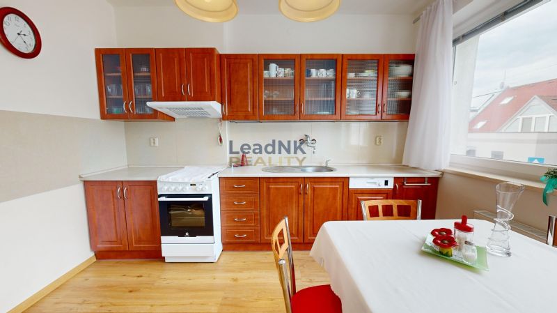 Küche in einer 3-Zimmer-Wohnung mit Holzschränken, Herd und Boden mit Holzdekor.