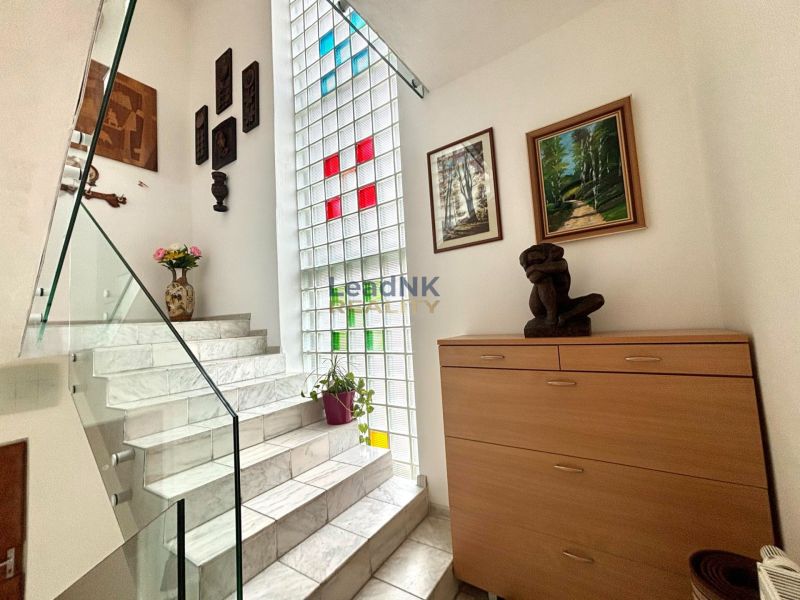 Schön beleuchtete Treppen mit Dekorationen, Kunstwerken und Blumen in einer 3-Zimmer-Wohnung.