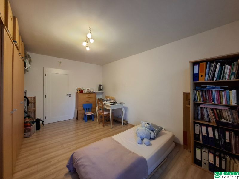 Ein Zimmer mit einem Schreibtisch, einem Bett und einem Boden in Holzoptik in einer 3-Zimmer-Wohnung.