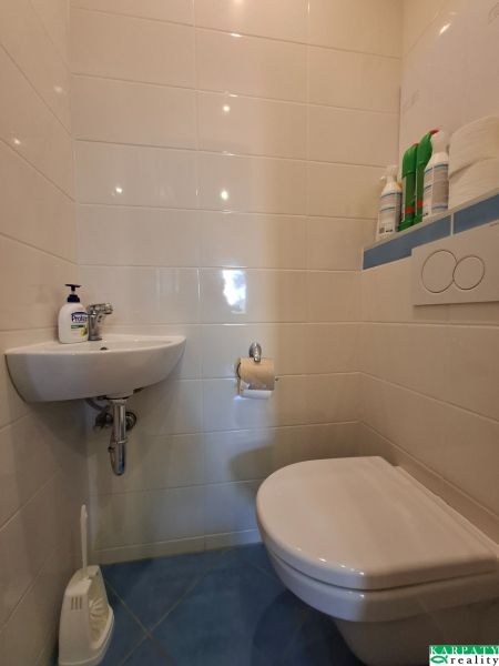 Die Toilette mit Waschbecken in der 3-Zimmer-Wohnung hat helle Fliesen.