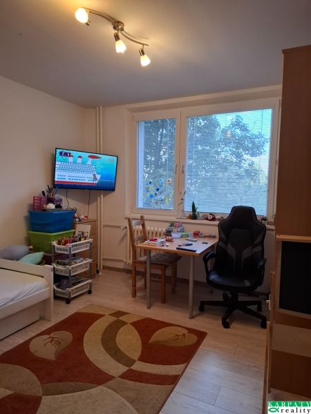 Kinderzimmer mit Bett, Tisch und Holzboden in einer 3-Zimmer-Wohnung.