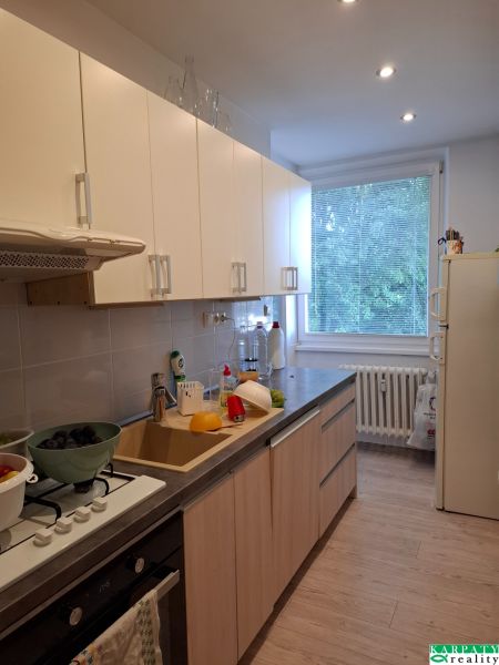 Küche in einer 3-Zimmer-Wohnung mit Holzboden und hellen Schränken.