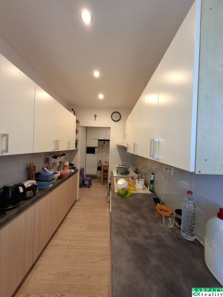 Küche in einer 3-Zimmer-Wohnung mit weißen Schränken und einem Boden in Holzoptik.