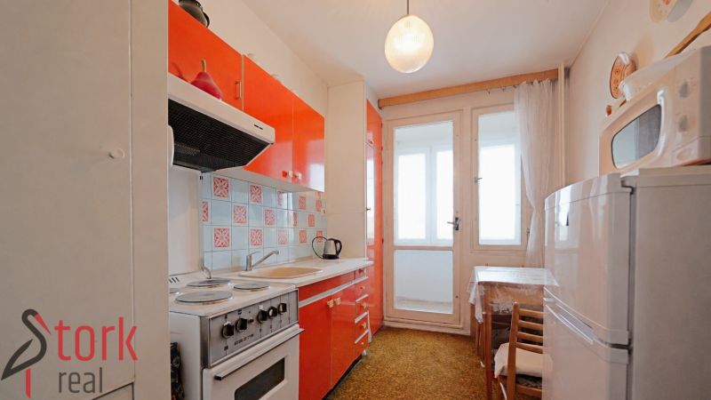 Küche in einer 2-Zimmer-Wohnung mit orangefarbenen Schränken und Balkontüren.