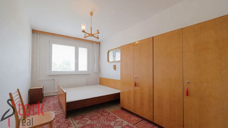 Schlafzimmer mit Bett, Schränken und Teppich in einer 2-Zimmer-Wohnung.