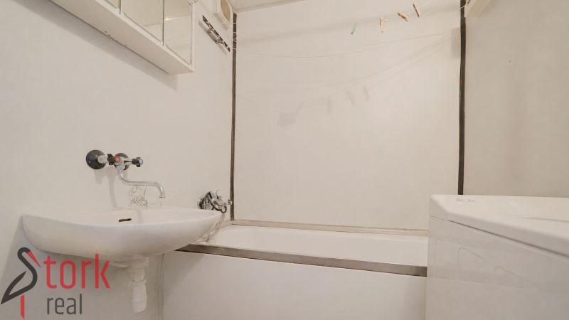 Badezimmer in einer 2-Zimmer-Wohnung mit Badewanne, Waschbecken und Waschmaschine.