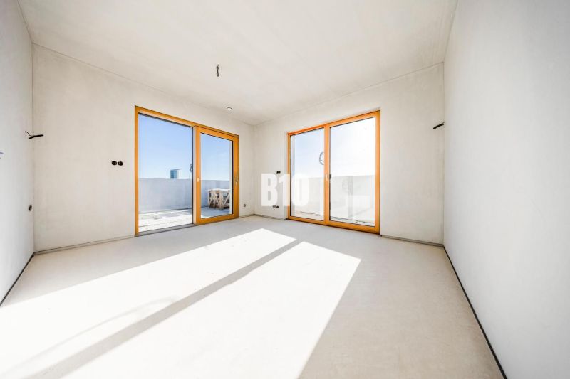 Ein geräumiges Zimmer mit großen Fenstern und Aussicht, helle Wände, 3-Zimmer-Wohnung.