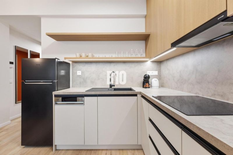 Küche in einer Einzimmerwohnung mit Holzboden und einem schwarzen Kühlschrank.