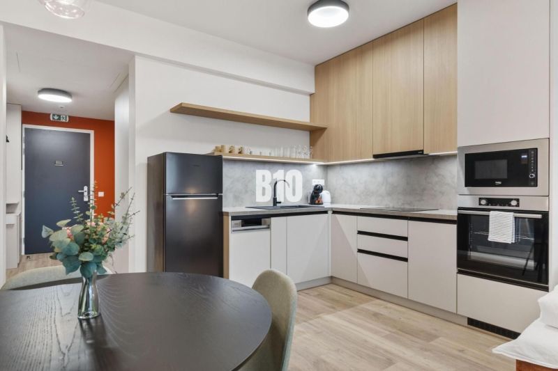 Küche mit Esstisch, Geräten und Holzboden in einer Einzimmerwohnung.