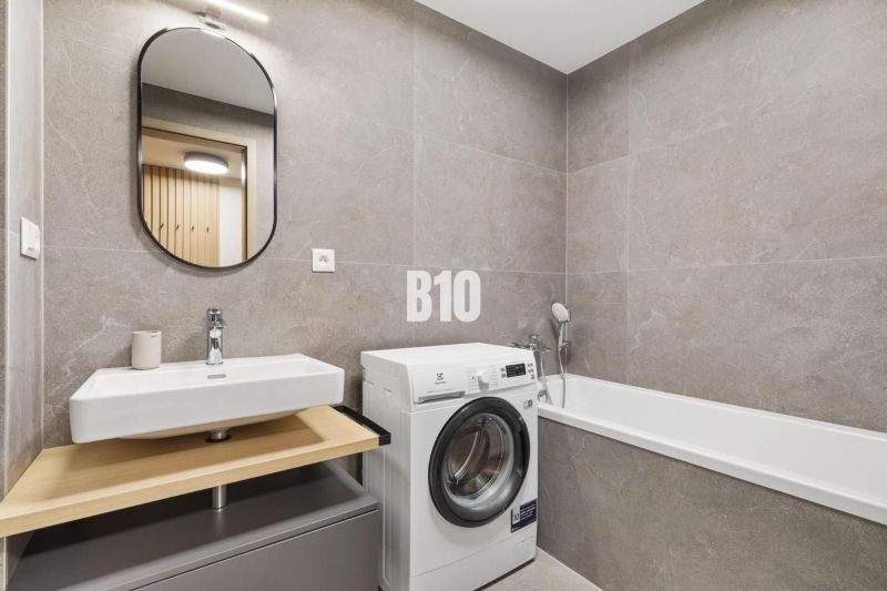 Badezimmer mit Waschbecken, Waschmaschine und Badewanne in einer Einzimmerwohnung.