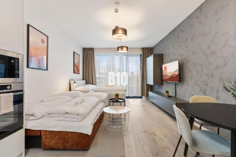 Ein komfortabler Wohnbereich in einer Einzimmerwohnung mit Holzboden und großen Fenstern.