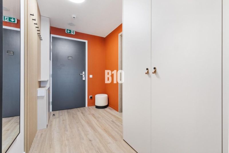 Eingangsbereich einer Einzimmerwohnung mit Holzboden und einer orangefarbenen Wand.