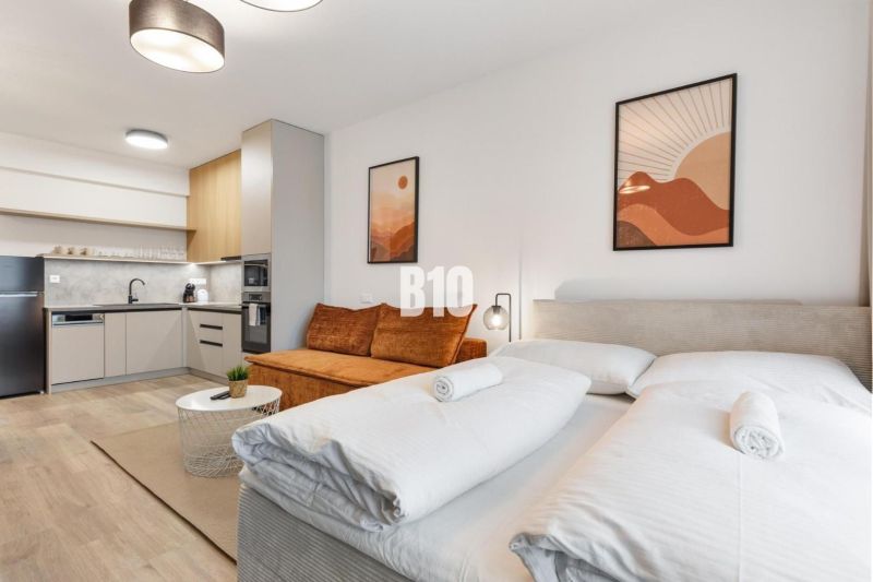 Innenraum einer Einzimmerwohnung mit Holzboden, Küche und Bett.