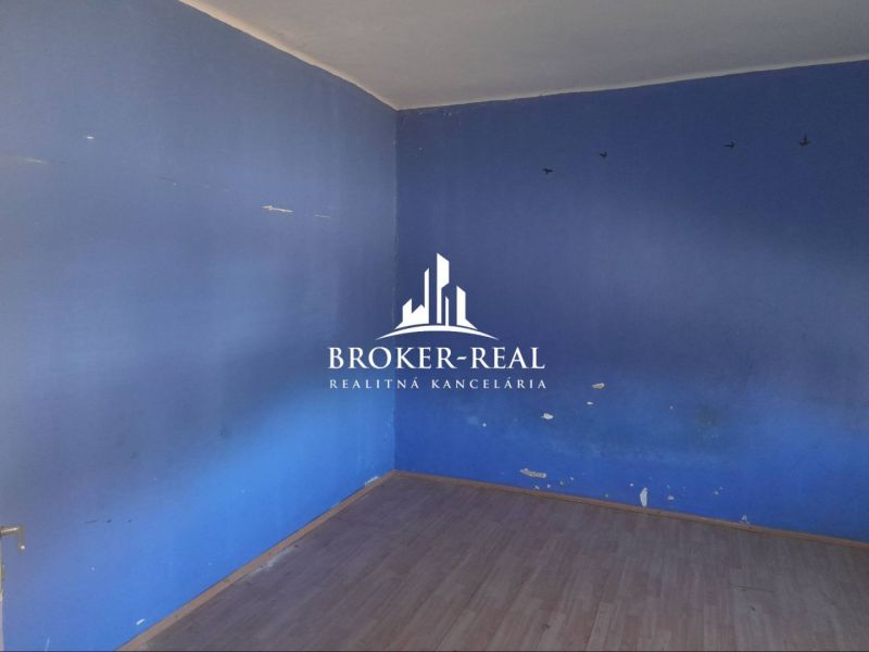 Ein Zimmer in einem Einfamilienhaus mit blauen Wänden und einem Boden in Holzoptik.