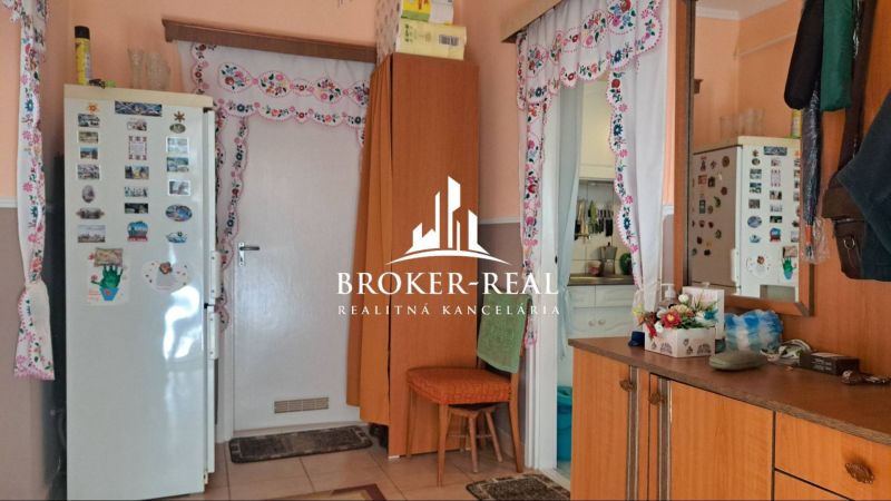 Innenraum eines Einfamilienhauses mit Küche, dekorativen Vorhängen und dekoriertem Kühlschrank.